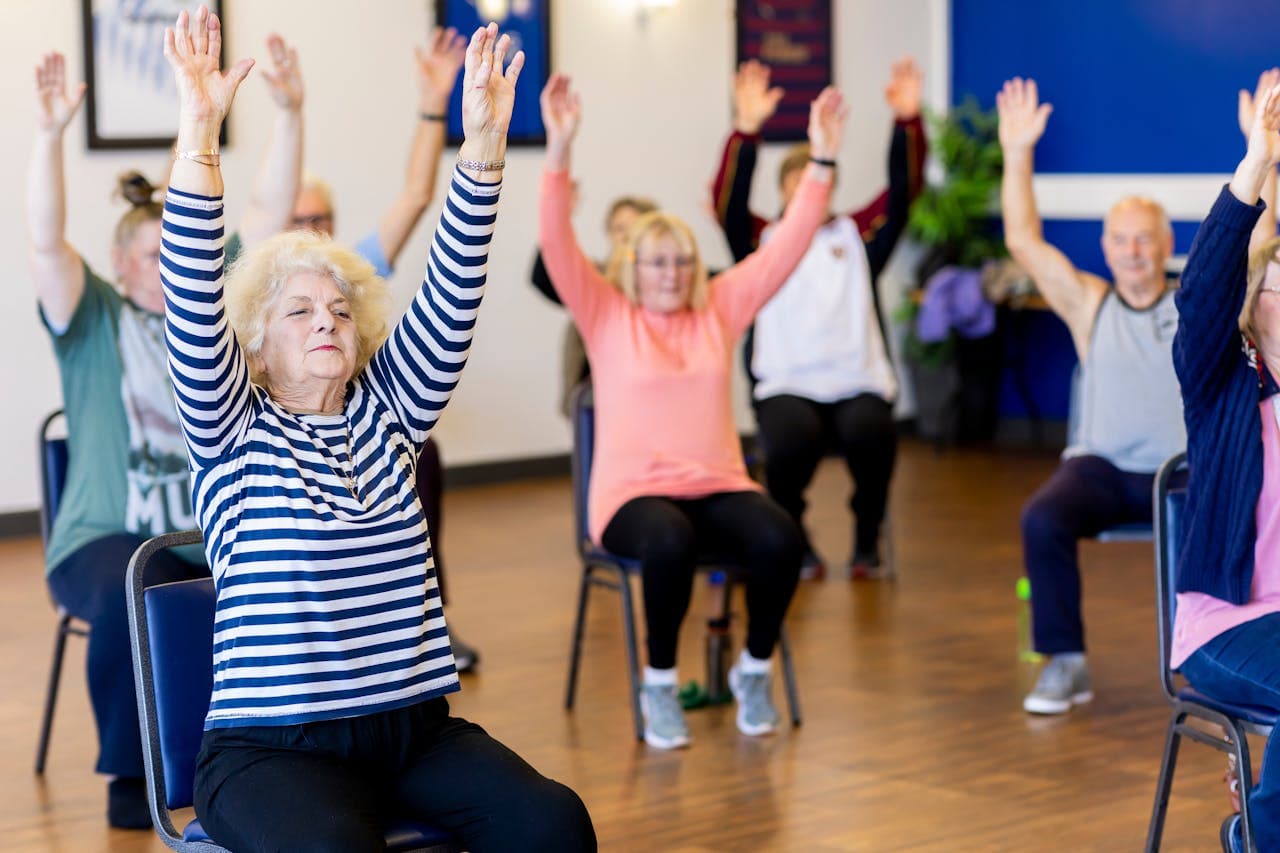 Older adults in a seated exercise class at a community center.