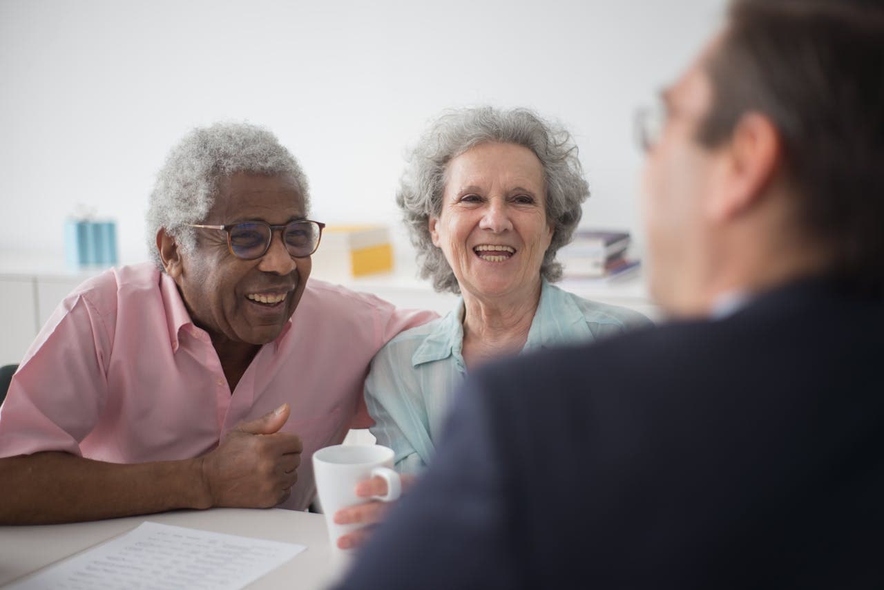 An older couple laughing with an advisor across a table.