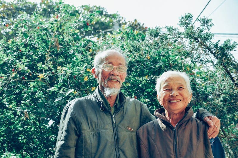 An older couple smiling together outdoors.