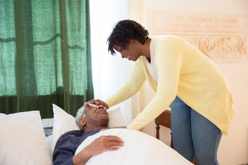 A caregiver helping an older man at home.